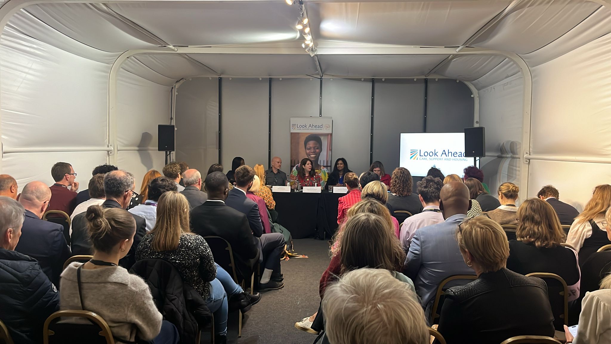 A busy conference room with key speakers and guests.